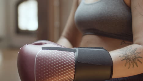 Close-up-shot-of-woman-putting-on-boxing-gloves-in-gym
